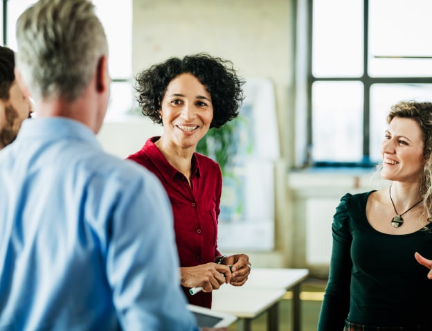 A photo of a group of people in business attire, smiling and engaging in conversation.