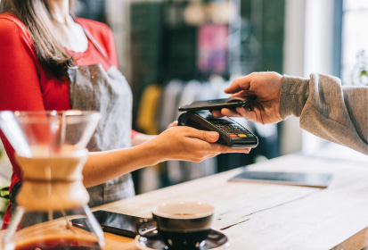 Barista with credit card device taking payment from customer